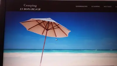 a pink umbrella sitting on a beach with the ocean at Camping Europa Beach in Castellare-di-Casinca