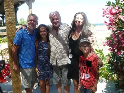 a family posing for a picture on the beach at Camping Europa Beach in Castellare-di-Casinca