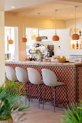 a kitchen with a bar with white stools at Casa Santini x Roc Seven in Porto-Vecchio