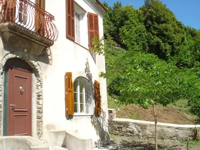 a building with a red door and a tree at Casa Defranchi in Sant Andrea di Bozio