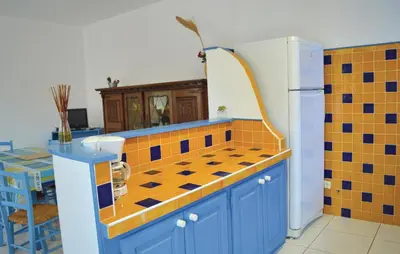 a kitchen with blue cabinets and orange and blue tiles at Cozy Apartment In Talasani in Talasani