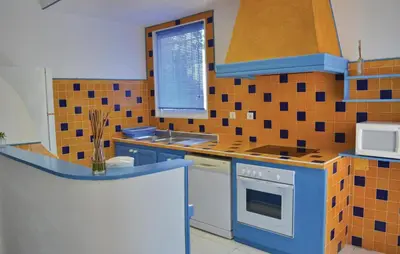 a kitchen with blue and orange tiles on the wall at Cozy Apartment In Talasani in Talasani