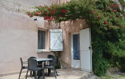 a table and chairs in front of a building with flowers at Cozy Apartment In Talasani in Talasani