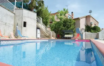 a swimming pool with chairs and a house at Cozy Apartment In Talasani in Talasani