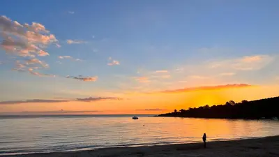 a person standing on the beach at sunset at Hotel Les Pavillons Du Golfe in Favone