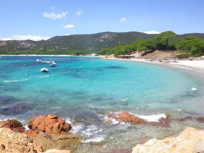 a beach with two boats in the water at Hotel Les Pavillons Du Golfe in Favone
