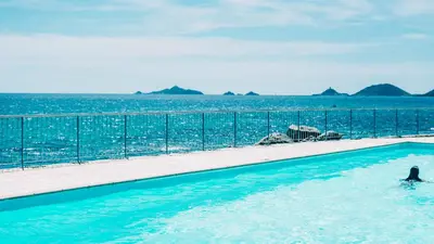 a person in a swimming pool next to the ocean at Hôtel Cala di Sole in Ajaccio