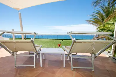 a patio with a table and chairs and the ocean at Hôtel Cala di Sole in Ajaccio