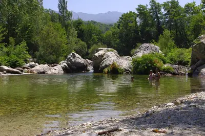 two people swimming in a river with rocks and trees at 95m2 au calme à 25mn AJACCIO, plages, linge inclus parking ok in Ucciani