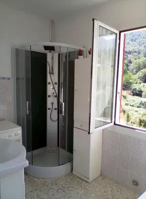 a bathroom with a shower and a toilet and a window at 95m2 au calme à 25mn AJACCIO, plages, linge inclus parking ok in Ucciani