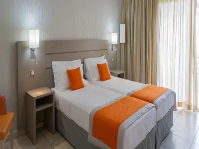 a hotel room with a large bed with orange pillows at Best Western Plus San Damianu in Sartène