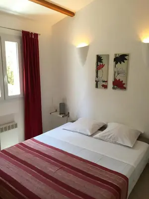 a bedroom with a large bed with a red curtain at residence stella d'oro in Porto-Vecchio