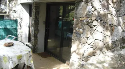 a stone building with a table and a glass door at Maisonnette du berger de Croccano in Sartène