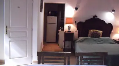 a bedroom with a bed and a white refrigerator at Maisonnette du berger de Croccano in Sartène