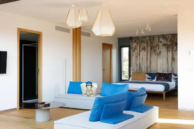 a bedroom with a bed and a couch with blue pillows at Hôtel & Spa Version Maquis Citadelle in Bonifacio