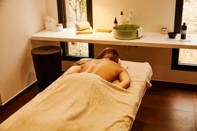 a naked woman laying on a bed in a bathroom at Hôtel & Spa Version Maquis Citadelle in Bonifacio
