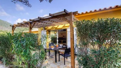 a patio with a table under a wooden pergola at Chez Muriel in Porto-Vecchio