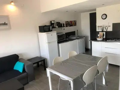 a living room with a table and a kitchen at Chez Muriel in Porto-Vecchio