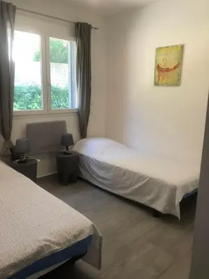 a bedroom with two beds and a window at Chez Muriel in Porto-Vecchio