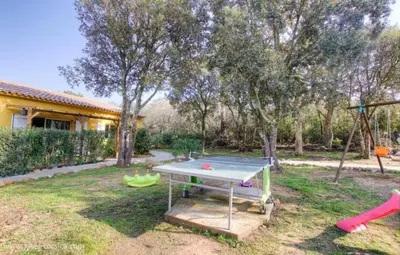 a ping pong table in a yard with a playground at Chez Muriel in Porto-Vecchio