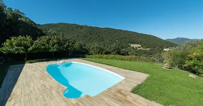 a blue swimming pool in a yard with mountains in the background at Au coeur de l'arriere Pays Rez de chaussé de Villa DOMAINE A PRESA in Sartène
