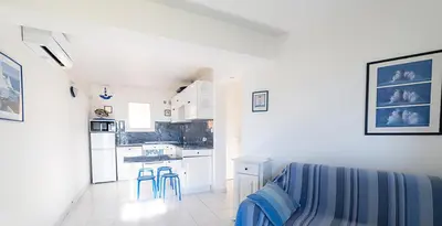 a kitchen with white cabinets and blue stools in a room at Au coeur de l'arriere Pays Rez de chaussé de Villa DOMAINE A PRESA in Sartène