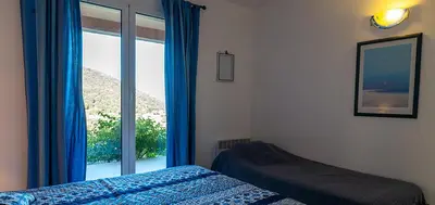 a bedroom with a bed and a large window at Au coeur de l'arriere Pays Rez de chaussé de Villa DOMAINE A PRESA in Sartène