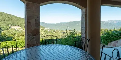 a table on a balcony with a view of mountains at Au coeur de l'arriere Pays Rez de chaussé de Villa DOMAINE A PRESA in Sartène