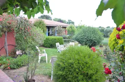 a garden with chairs and flowers and a house at CASA-CORSA chambre d'hote in Cervione