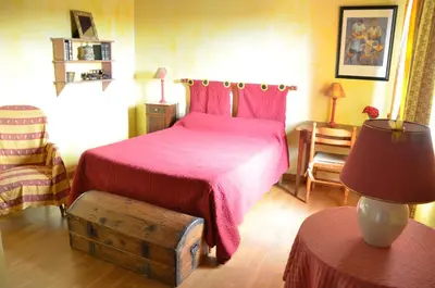 a bedroom with a pink bed and a table with a lamp at CASA-CORSA chambre d'hote in Cervione