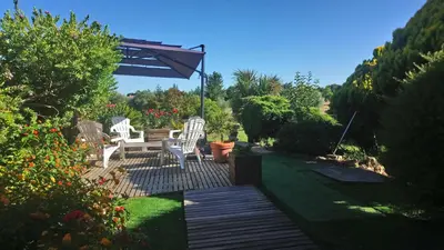 a patio with two white chairs and an umbrella at CASA-CORSA chambre d'hote in Cervione
