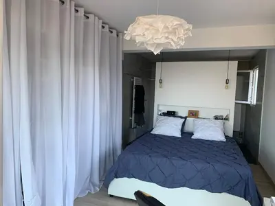 a bedroom with a blue bed and a chandelier at Chez Marc et Jeannick in Belvédère