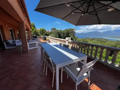 a table and chairs on a balcony with an umbrella at Chez Marc et Jeannick in Belvédère