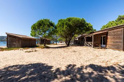 a house on a beach next to a building at Camping Golfo Di Sogno in Porto-Vecchio