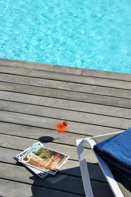 a magazine and a drink on a table next to a pool at Résidence MARINA SERENA in Porto-Vecchio