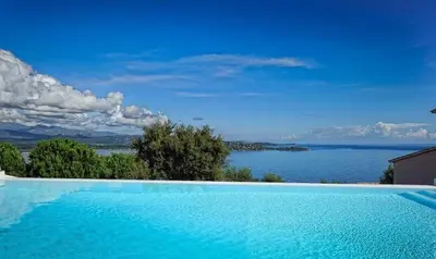 a large blue swimming pool with a view of the water at Résidence MARINA SERENA in Porto-Vecchio