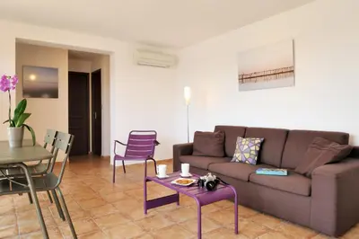 a living room with a couch and a table and chairs at Résidence MARINA SERENA in Porto-Vecchio
