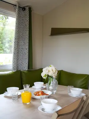 a table with plates of food and a vase of flowers at Camping Le Damier in Pianottoli-Caldarello