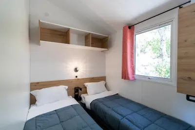 two beds in a small room with a window at Camping Le Damier in Pianottoli-Caldarello