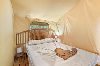 a bed in a tent with a towel on it at Camping Le Damier in Pianottoli-Caldarello