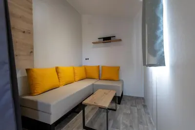 a white couch with yellow pillows and a wooden table at Camping Le Damier in Pianottoli-Caldarello