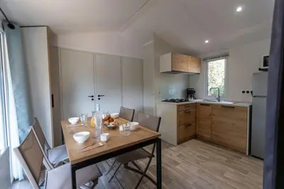 a kitchen with a wooden table and chairs in a room at Camping Le Damier in Pianottoli-Caldarello