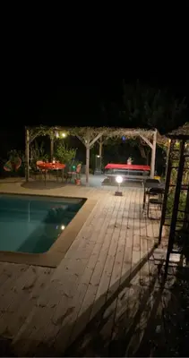 a patio with a table and a pool at night at Macchia Évasion avec piscine in Monacia-dʼAullène
