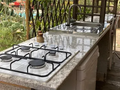 a stove top oven sitting next to a sink at Macchia Évasion avec piscine in Monacia-dʼAullène