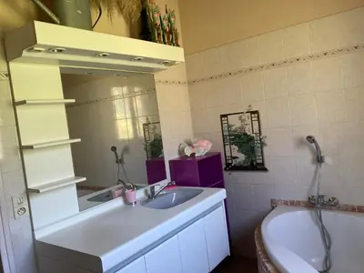 a bathroom with a sink and a tub and a mirror at Macchia Évasion avec piscine in Monacia-dʼAullène