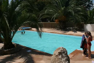 two women standing next to a swimming pool at Camping Via Romana in Prunelli-di-Fiumorbo