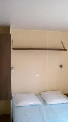 a bed with two white pillows on top of it at Camping Via Romana in Prunelli-di-Fiumorbo