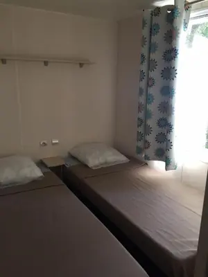 two beds in a small room with a window at Camping Via Romana in Prunelli-di-Fiumorbo