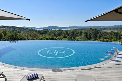 a large swimming pool with a view of the water at Hotel U Paesolu in Sainte-Lucie de Porto-Vecchio