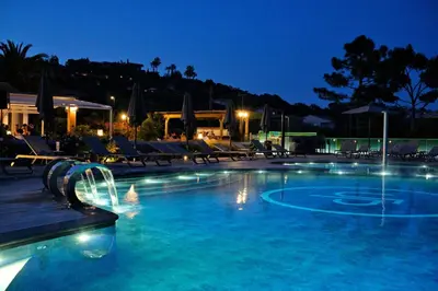 a swimming pool at night with chairs and lights at Hotel U Paesolu in Sainte-Lucie de Porto-Vecchio
